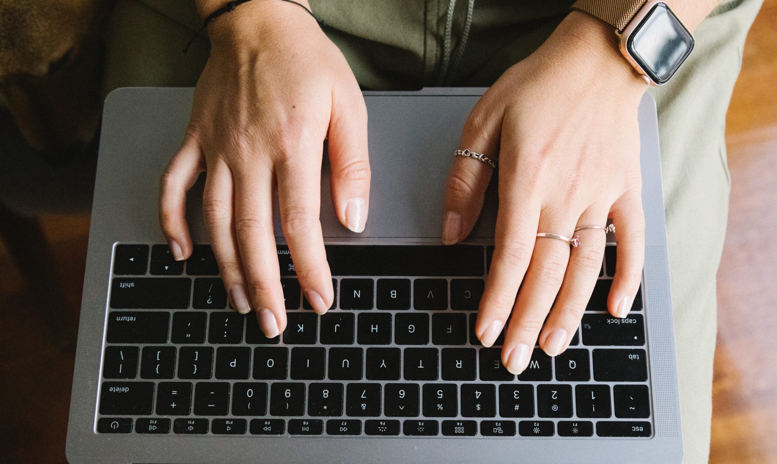 A photo of a person typing on a laptop keyboard from an overhead view.